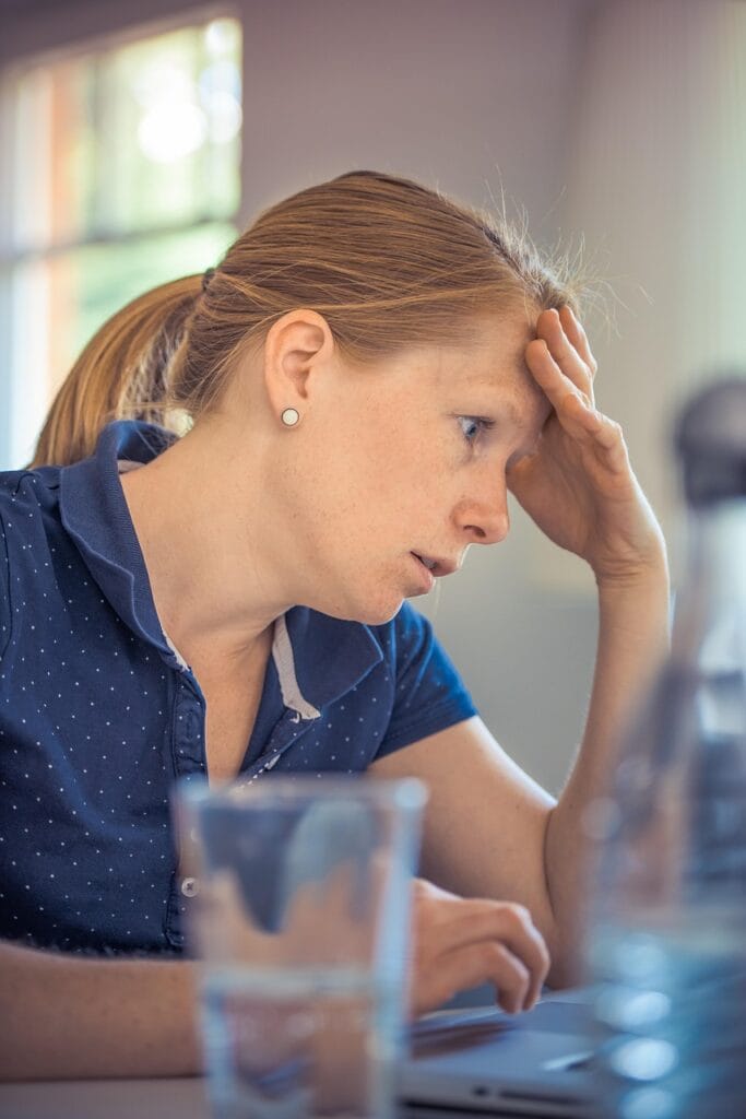 Stressed woman working at laptop, showing early signs of burnout and existential anxiety common in high-achieving professionals.